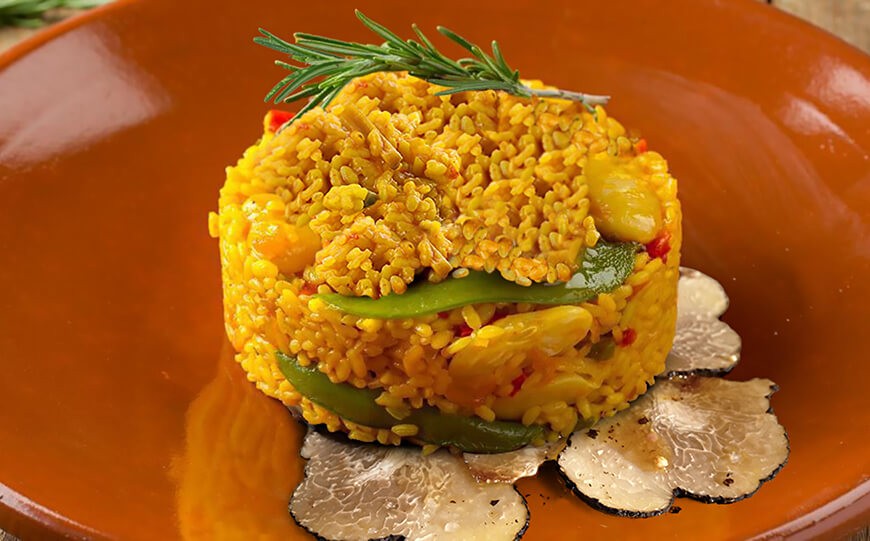 Paella de arroz con pollo, verduras y trufa de verano